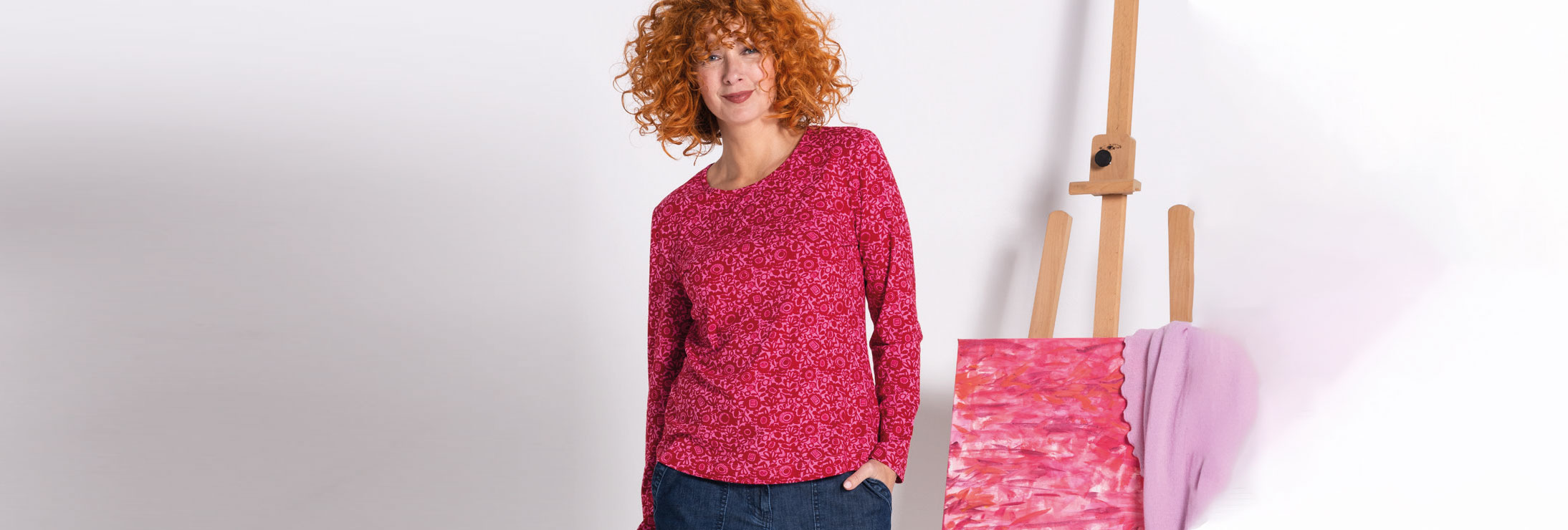 Fröhliche Frau mit roten Locken präsentiert Mode des Labels Heidekönign