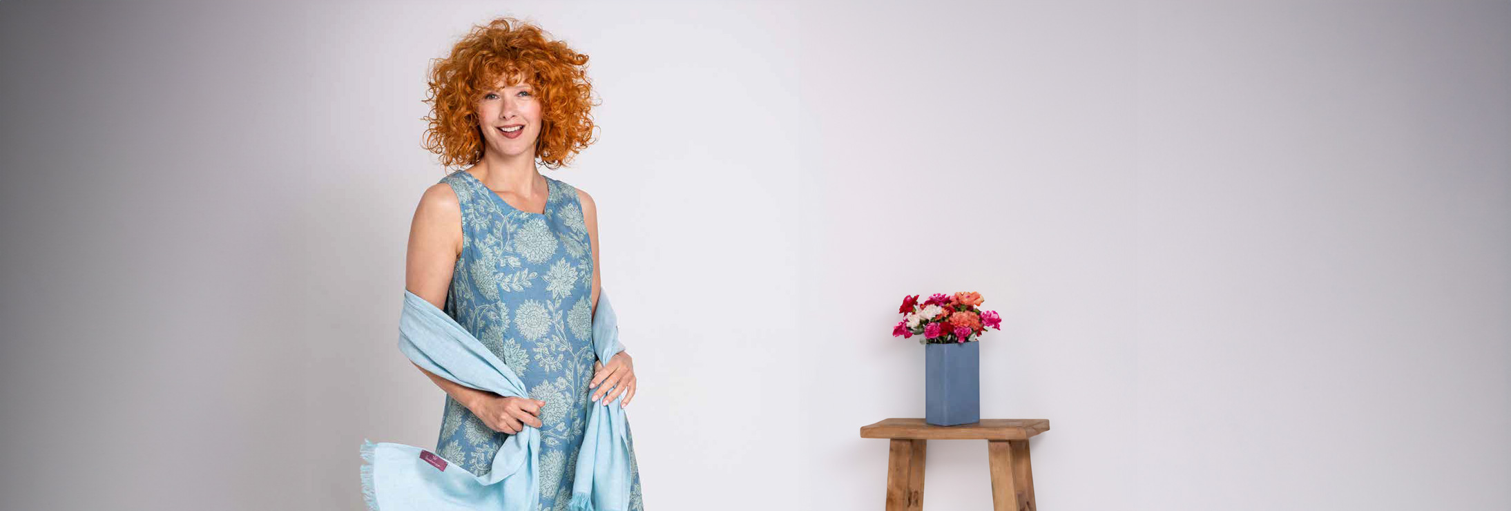 Fröhliche Frau mit roten Locken präsentiert Mode des Labels Heidekönign